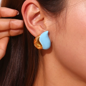 Close-up of model wearing gold and blue enamel teardrop earrings with a metal finish
