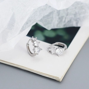Macro detail of 925 sterling silver hoop earrings with three shining zircon stones