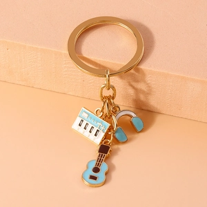 Detail of keychain with blue guitar, piano keyboard and headphone charms on gold ring