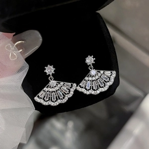 Macro shot of silver fan-shaped earrings with white zircons on a black jewelry box