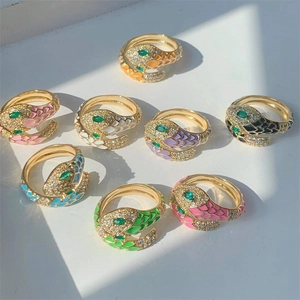 Detailed view of colorful enamel snake rings with green zircon eyes and golden finish