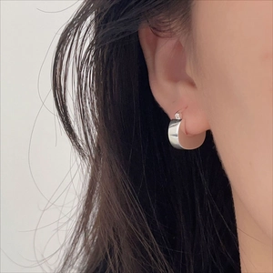 Close-up of polished silver U-shaped hoop earring worn on a model with sleek finish