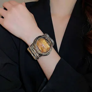 Manchette tressée dorée avec grand cristal ambré sur fond de costume noir élégant