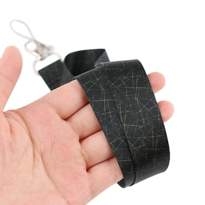 Detail of black fabric lanyard with yellow geometric patterns and metal buckle held by hand