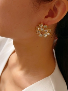 Detail of geometric sunburst earrings with clear crystals on gold metal base