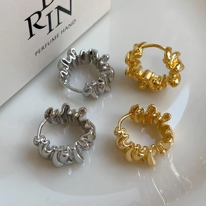 Irregular textured gold and silver metal hoop earrings with molten lava design