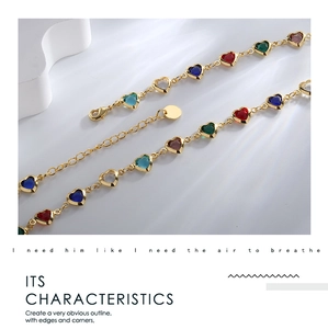 Macro detail of gold link necklace with colorful heart-shaped zircon stones and lobster clasp