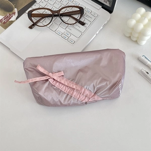 Close-up of pink glossy quilted pencil case with bow detail on white desk setup