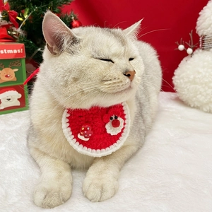 Détail d'un bavoir de Noël en crochet rouge avec bonhomme de neige sur un chat blanc