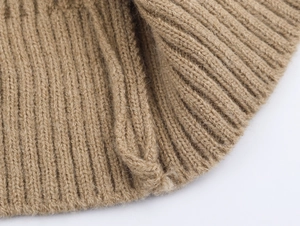 Macro shot of camel knit cardigan fabric showing detailed ribbed texture and soft yarn