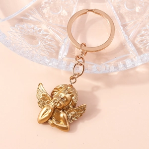 Macro shot of gold angel keychain with fine wing texture and matte metal finish