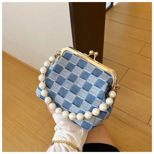 Detail of denim checkered mini bag featuring pearl bead handle and gold metal clasp