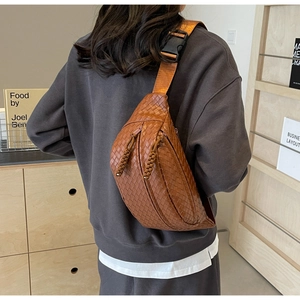 Brown woven faux leather chest bag worn across the back with adjustable strap and tassels