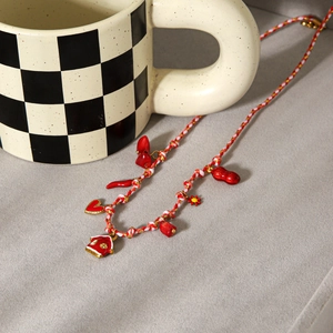 Collier en corde tressée avec pendentifs cœur, maison et fleurs rouges sur fond gris