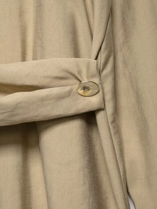 Close-up of khaki silky fabric texture with elegant oval metallic gold buttons detail