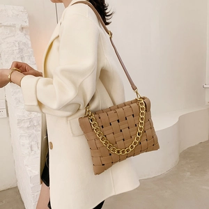 Creative woven caramel leather shoulder bag with gold chain strap on a model wearing white