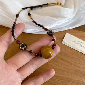 Detail der Vintage Perlenkette mit braunem Harzanhänger und goldenen Zwischenperlen