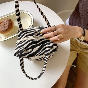 Close-up of zebra pattern fabric handbag with zipper and Love Sozakka label on a white table