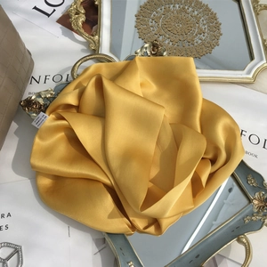 Detail of a bright yellow 100% mulberry silk scarf folded into an elegant rose shape