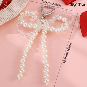 Detail view of woven pearl bow keychain with size and weight specs on pink background