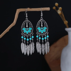 Detail of silver bohemian dangle earrings with blue beads and metal feather tassels
