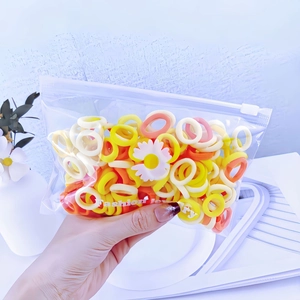 Close-up of colorful elastic hair bands with daisy charms in a zipper bag