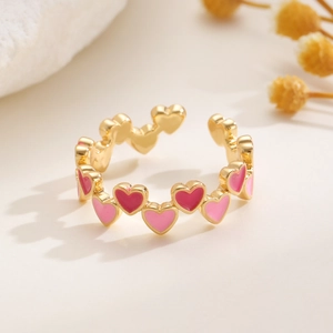 Makroaufnahme von verstellbarem Goldring mit herzförmigem rosa Emaille-Muster