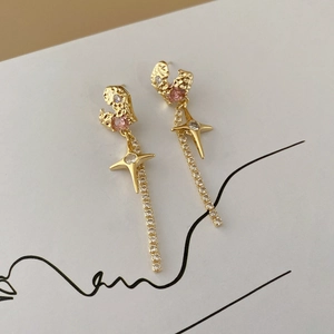 Detail of gold tassel earrings with zircon hearts, four-pointed stars and sparkling rhinestones