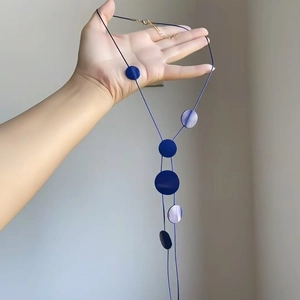Detail view of the long minimalist necklace with glossy deep blue circular pendants