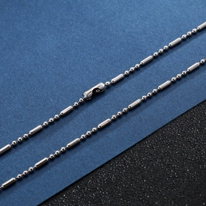Collier en acier inoxydable argenté avec perles et barres sur fond texturé