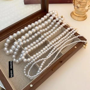 Colliers de perles vintage de tailles variées présentés dans une boîte en bois