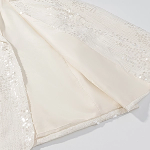 Dettaglio ravvicinato del tessuto con paillettes beige, fodera liscia e cuciture fini