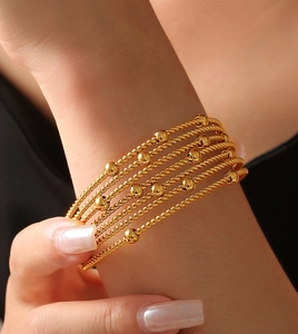 Detail of multi-layer gold titanium steel bracelet with twisted rope and bead accents
