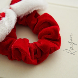 Detail of red velvet hair scrunchie with white faux fur trim and soft fabric texture