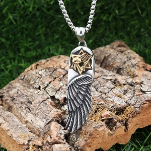 Detail of vintage steel feather pendant with star and eye icons on rustic wood bark