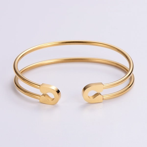 Detailed close-up of a double-track hollow open bangle in warm golden stainless steel finish