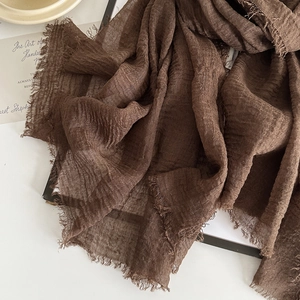 Detail of dark brown cotton linen scarf showing raw fringe edges and crinkled texture