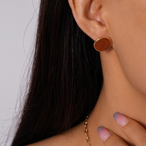 Gros plan d'une boucle d'oreille ronde brun-rouge avec un bord doré élégant