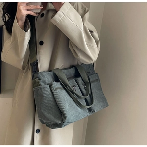 Detail view of large dark green corduroy tote bag with front zip pockets on model