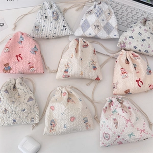 Flat lay of nine cartoon drawstring storage bags with cute animal and floral patterns
