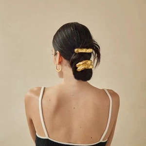 Detail of gold metal hair clips and earrings set featuring molten lava texture on model