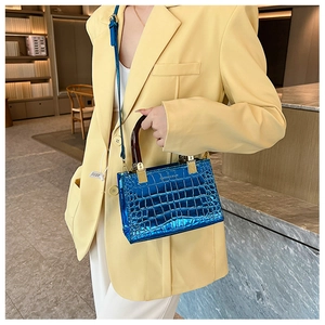 Detail of glossy blue crocodile embossed box bag with tortoiseshell handle and gold hardware
