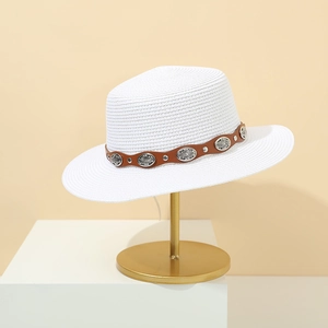 Detailed shot of white straw sun hat with brown leather band and ornate silver buckles