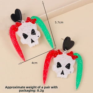 Detailed view of skull earrings with size labels 5.7cm by 4cm and black heart studs