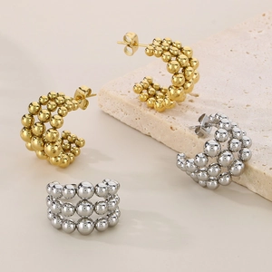 Macro detail of three-row metallic beaded stud earrings in gold and silver finish