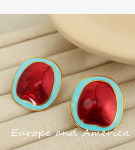 Detailed macro shot of irregular geometric earrings with red and blue enamel in gold frame