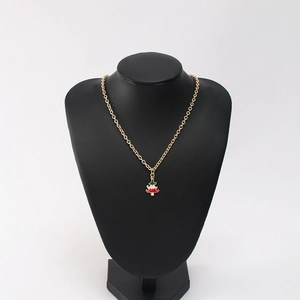 Close-up of a festive Christmas tree pendant with red and green enamel on a gold chain