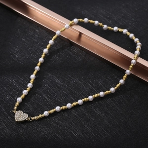 Detail of white pearl and gold bead necklace with a sparkling heart pendant centerpiece