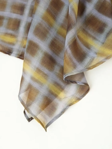 Close-up of lightweight plaid fabric showing translucent texture and soft brown check pattern