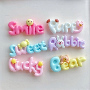 Detailed view of colorful resin DIY charms including Smile and Puppy designs in pastel colors